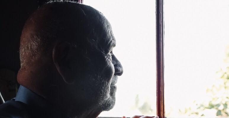 an elderly man looking out a window